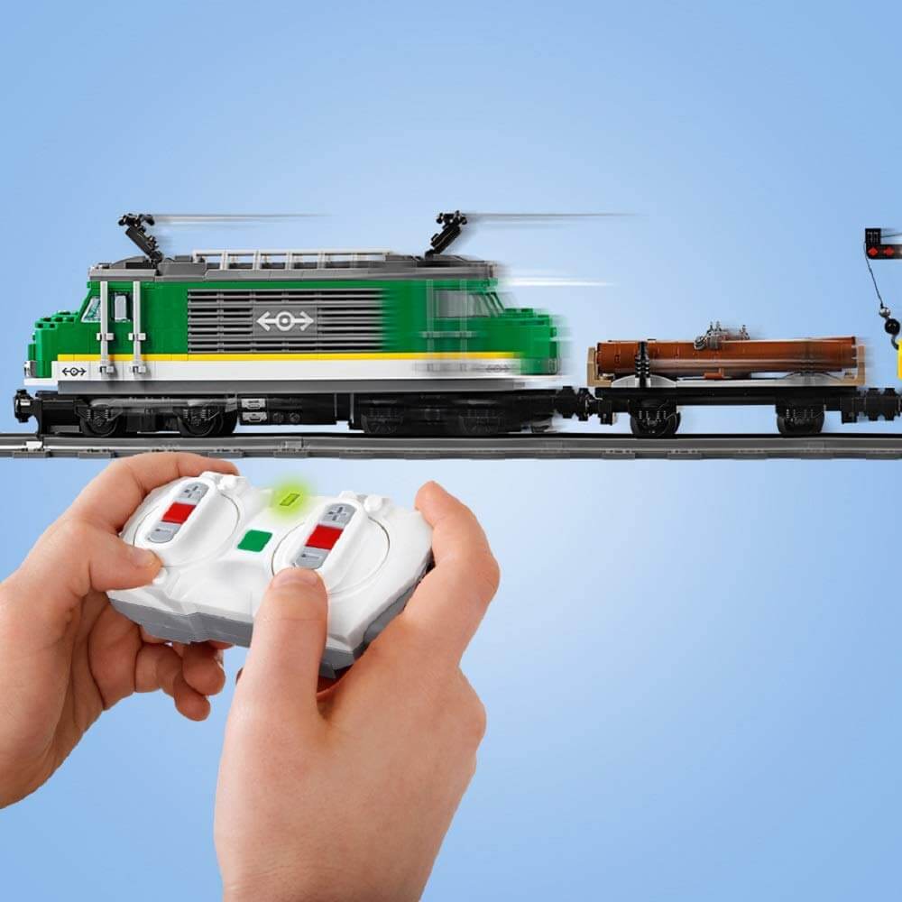 Child's hands using Bluetooth remote control for LEGO® City Cargo Train 60198, showcasing the motorized engine in motion.