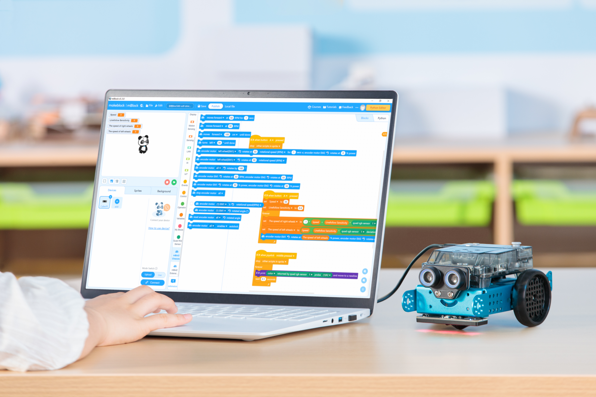 User programming the Makeblock mBot 2 educational robot on a laptop with visual coding interface.