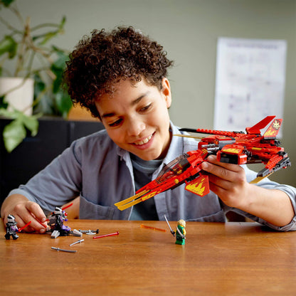 Child playing with LEGO NINJAGO Legacy Kai Fighter jet and minifigures in a creative setting.
