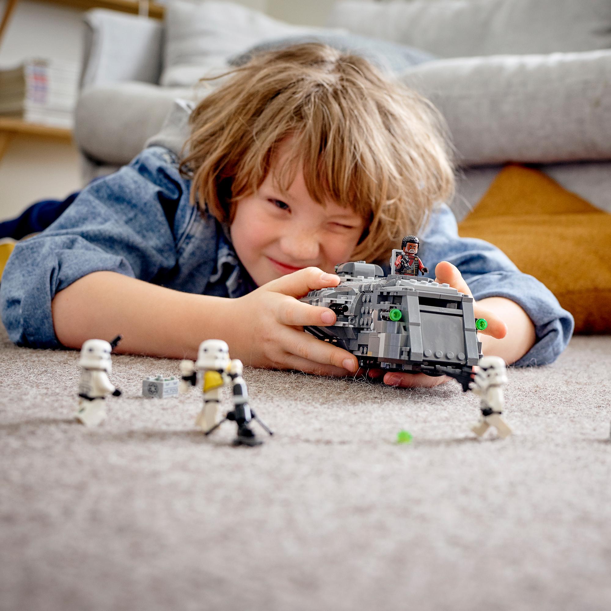 Child playing with LEGO® Star Wars Imperial Armoured Marauder Set 75311 and Stormtroopers on carpet.