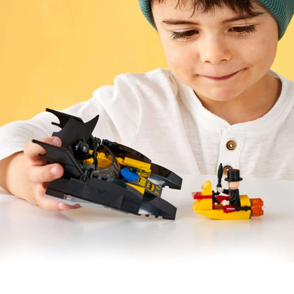 Child playing with LEGO DC Batman Batboat and The Penguin minifigure, engaging in creative superhero fun.