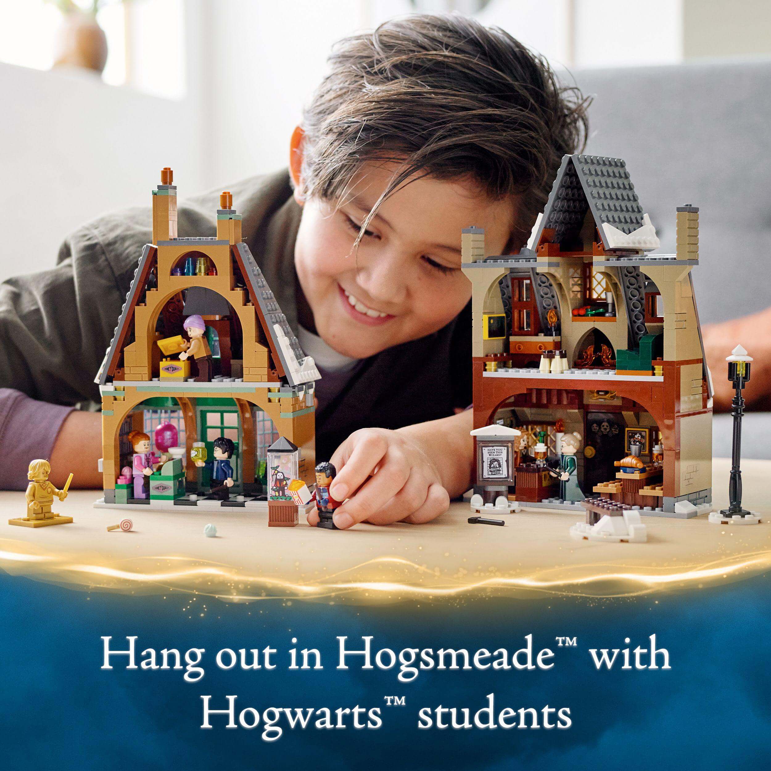 Child playing with LEGO® Harry Potter Hogsmeade Village set, featuring Hogwarts™ students and village shops.