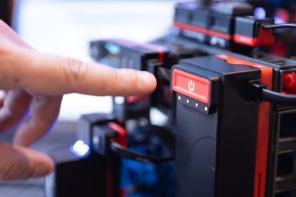 Close-up of a hand pressing the power button on a Sphero engineering kit for robotics education.