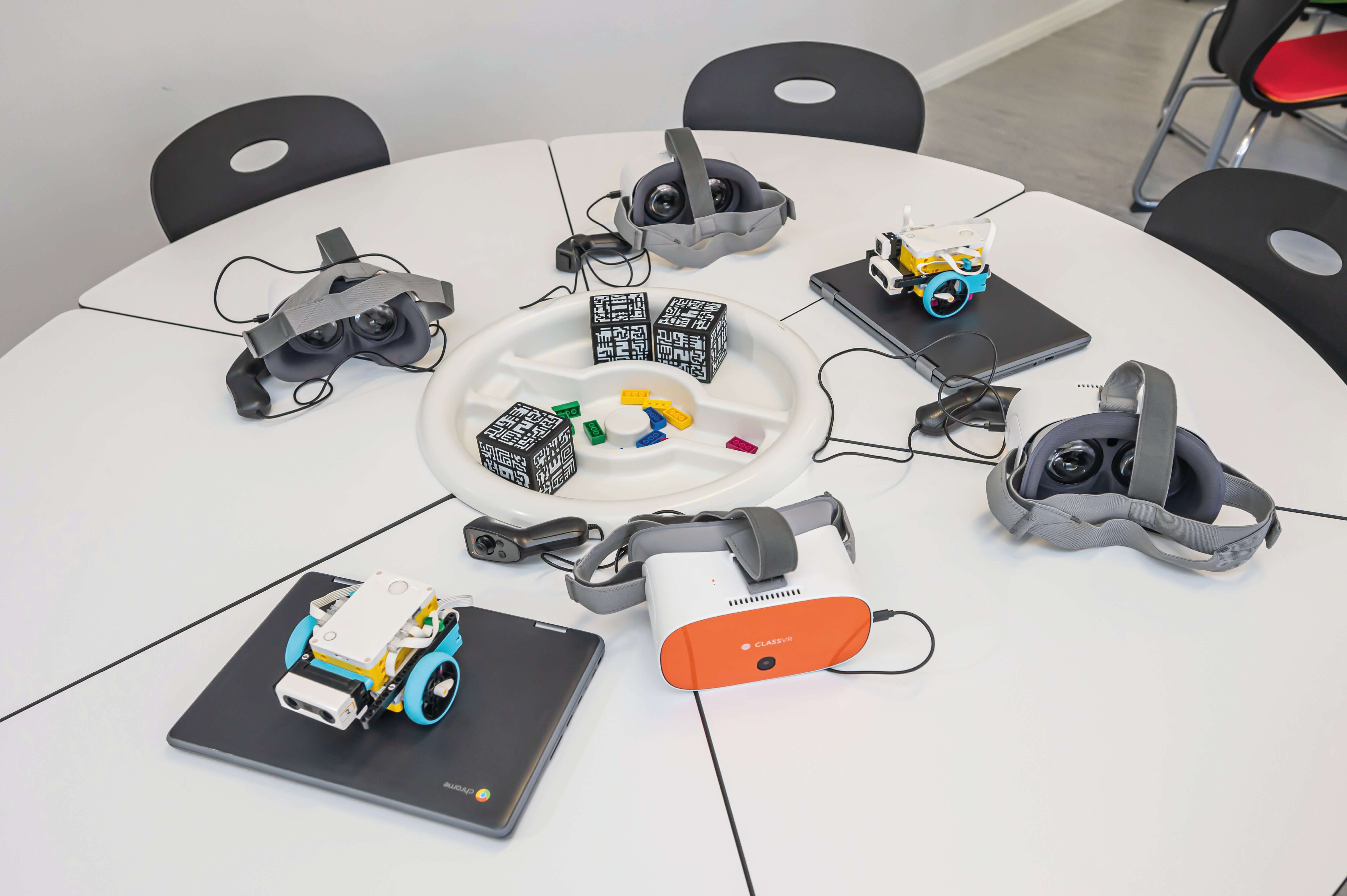 Innovative educational tools including VR headsets and robotic kits on a table for hands-on learning.