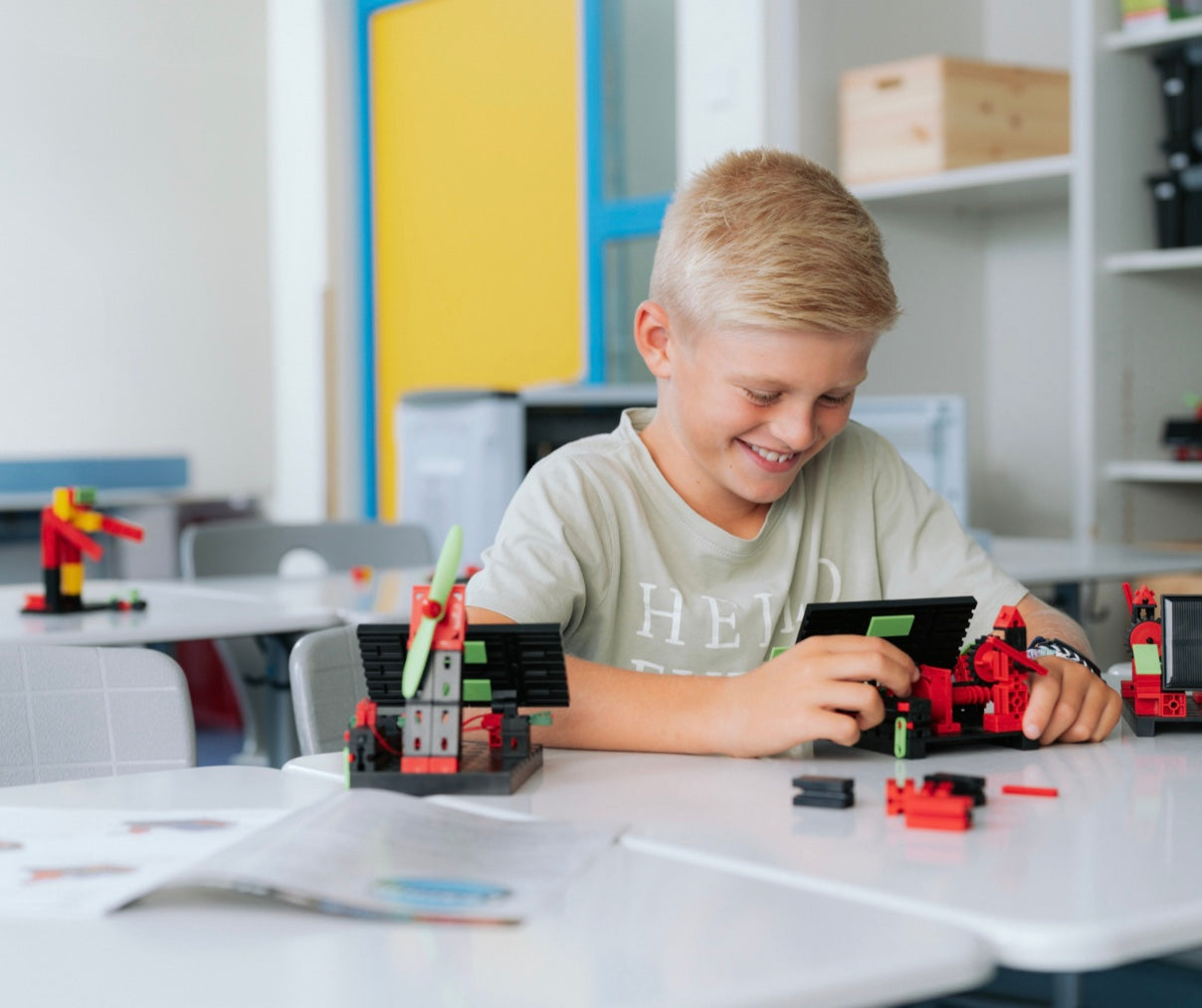 Boy happily building with colorful toys in a classroom, showcasing creativity and hands-on learning.