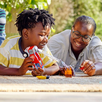 Child playing with LEGO® City Fire Ladder Truck Toy alongside a smiling adult, enjoying creative building fun.