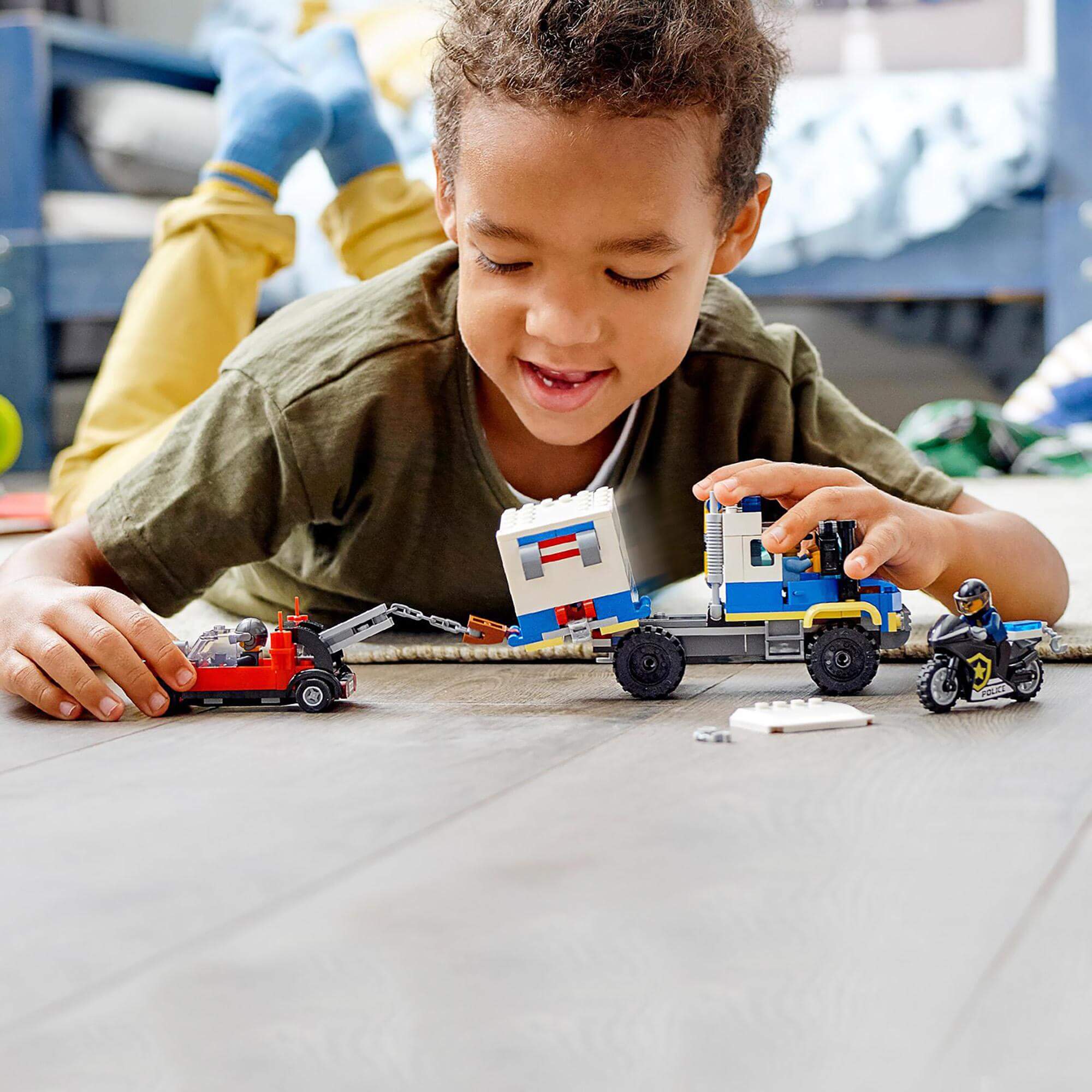 Child playing with LEGO City Police Prisoner Transport Truck Toy 60276, featuring vehicles and fun characters.