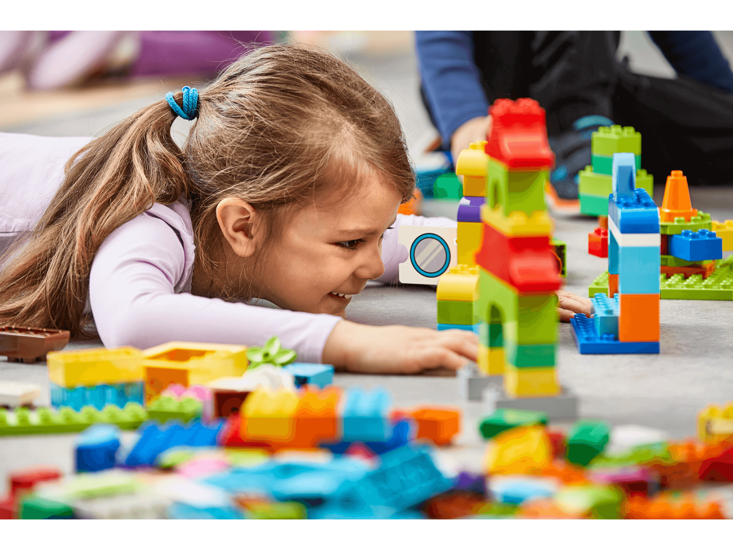 A young girl engaged in interactive play with colorful LEGO® blocks, enhancing creativity and learning.