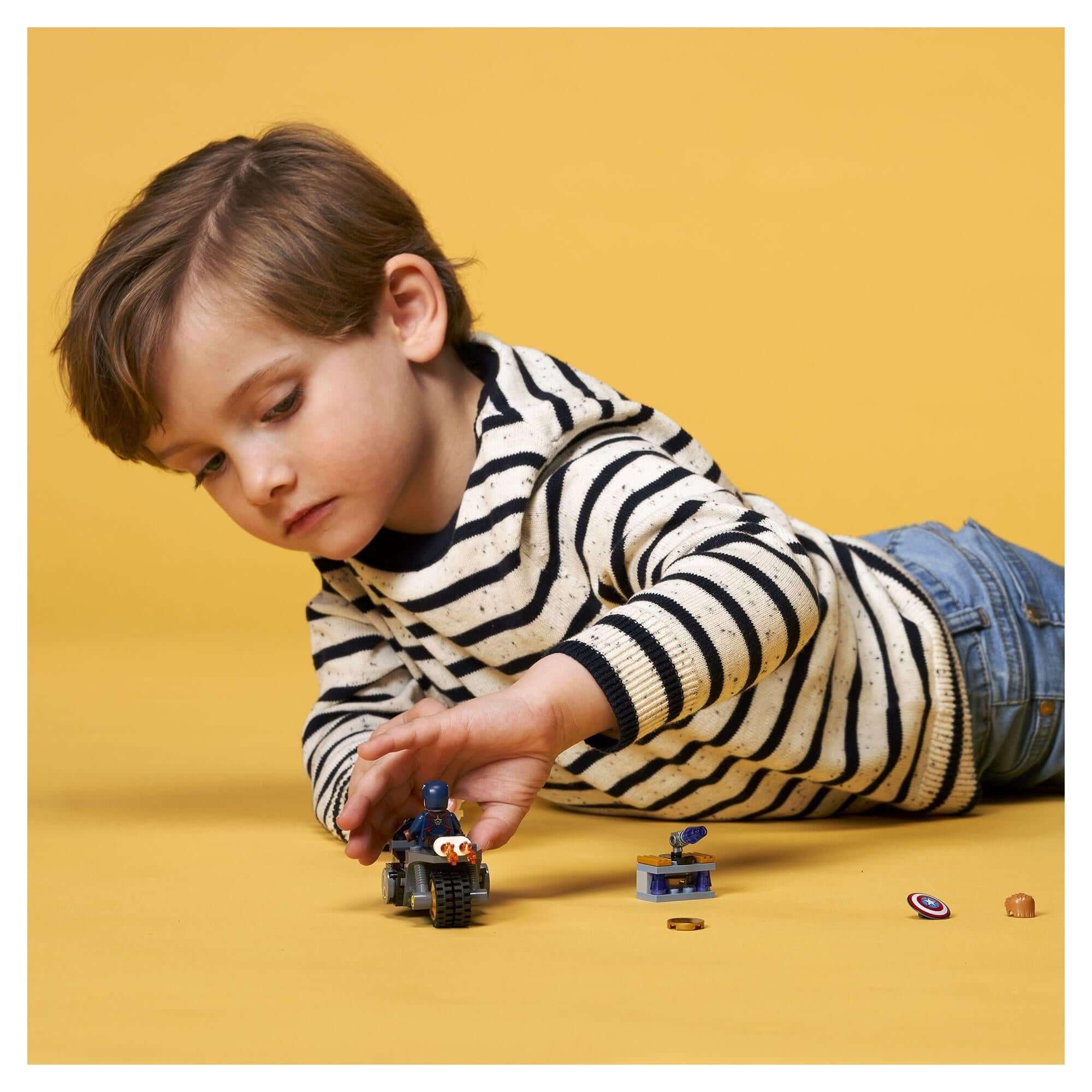 Child playing with LEGO® Marvel Captain America set 76189, featuring motorcycle and Hydra agent toys.