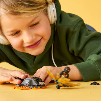 Child playing with LEGO® NINJAGO Spinjitzu Burst Cole Spinner Toy 70685, launching Cole into the air.