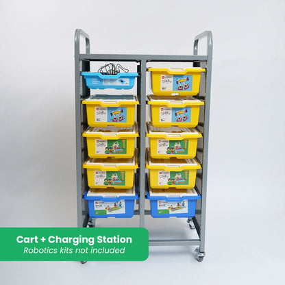 A grey metal mobile storage cart shown with various LEGO Education SPIKE and BricQ kits. The top-left slot contains a blue charging tray with multiple cables. A green banner at the bottom reads "Cart + Charging Station - Robotics kits not included."