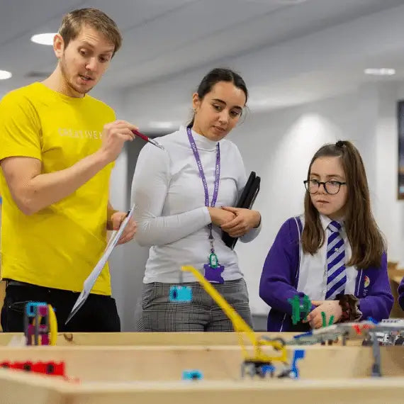 Students engaging in hands-on robotics lesson with an instructor, promoting STEM education and creativity.