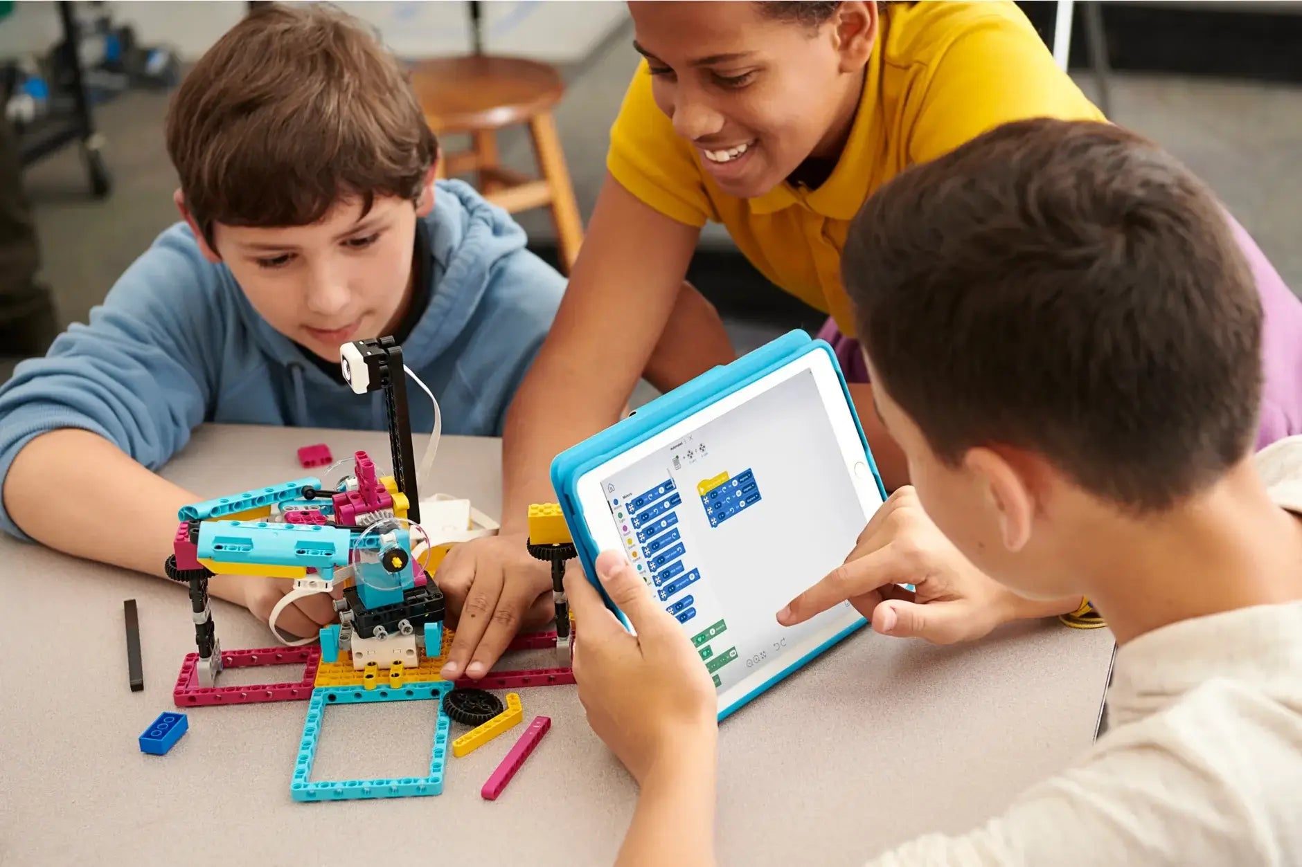 Children collaborating on a robotics project using building blocks and a tablet for programming.