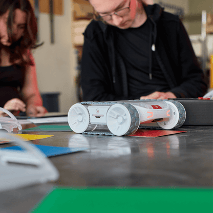 Sphero RVR+ robot on a table with students engaged in a programming activity, showcasing hands-on learning.