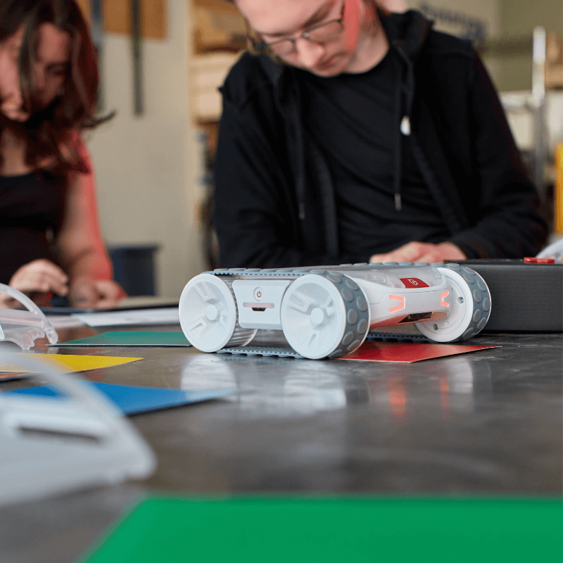 Sphero RVR+ robot on a table with students engaged in a programming activity, showcasing hands-on learning.