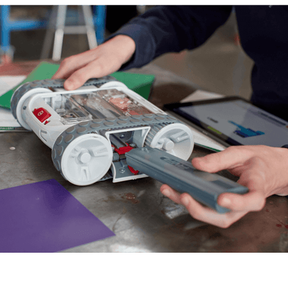 Hands inserting battery into Sphero RVR+ programmable robot, showcasing its customizable design and technology.