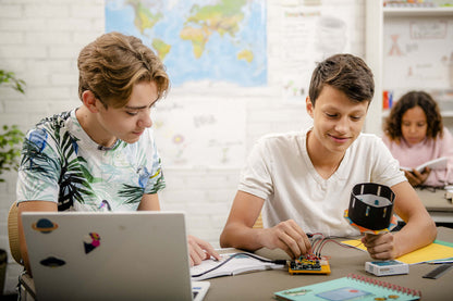 Students engaged in hands-on electronics projects with an Arduino education starter kit in a classroom.