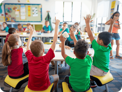 Students engaged in a classroom activity, raising hands enthusiastically during an interactive lesson.