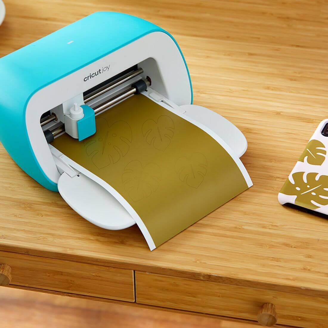 Cricut Joy machine cutting smart vinyl on a wooden table, showcasing crafting capabilities and convenience.