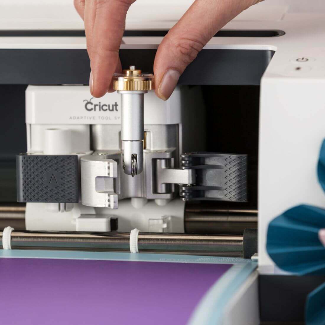 A hand attaching a scoring wheel to a Cricut Maker for crafting projects.