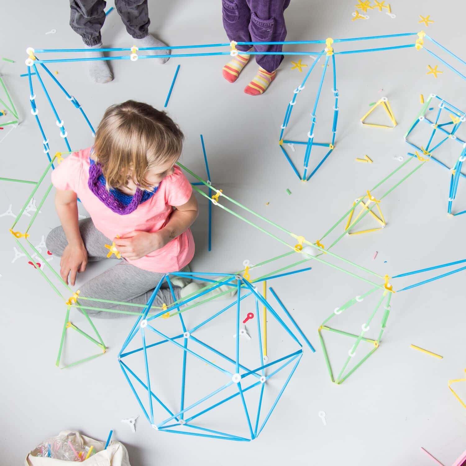 Children building colorful structures with bendy straws and challenge cards from the Imagination Kit.