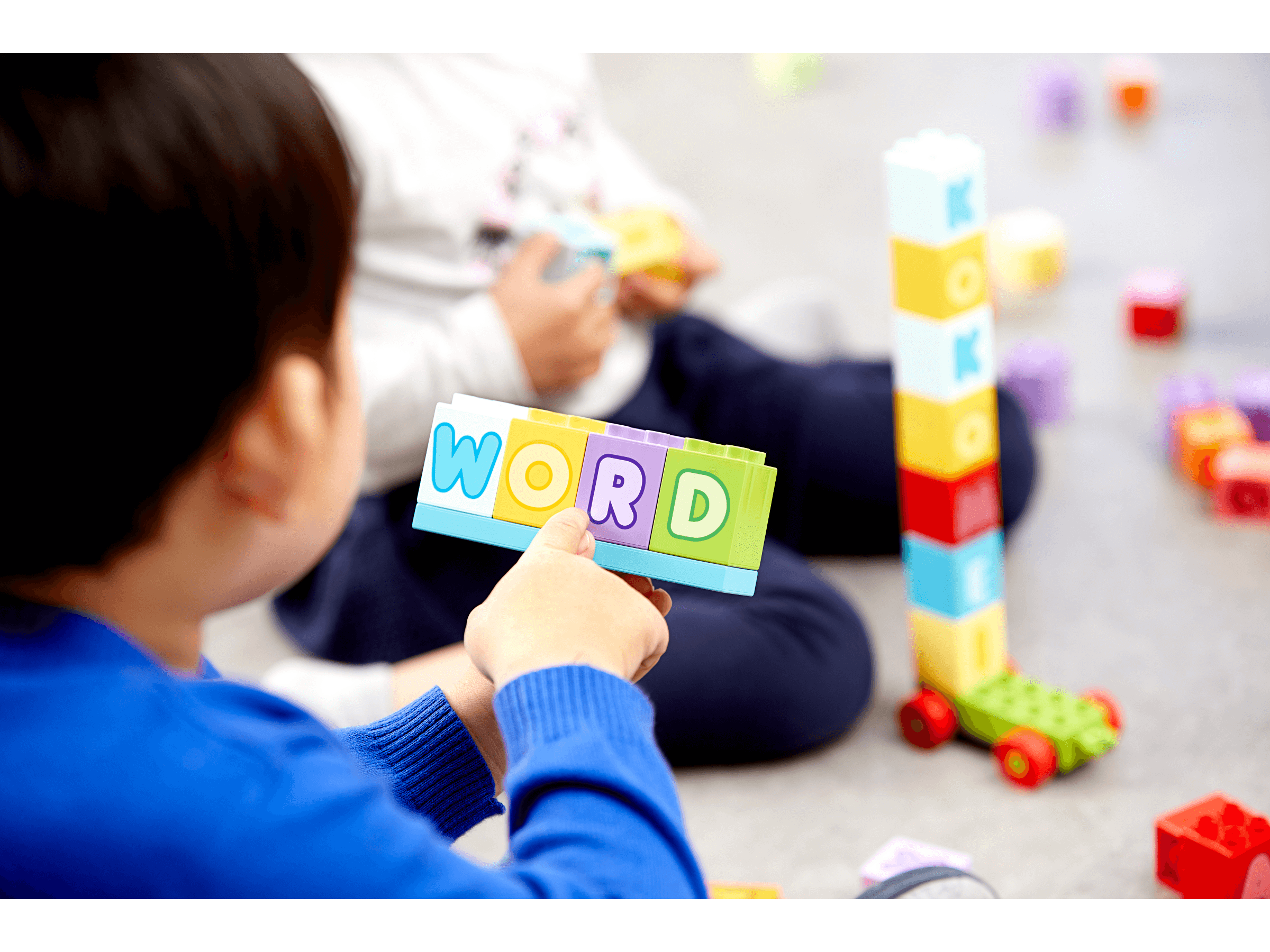 Child playing with colorful LEGO® bricks, spelling the word 'WORD' while learning the alphabet with LEGO® Education Letters.