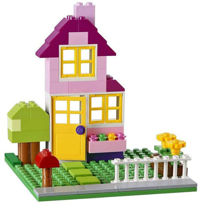 Colorful LEGO house model with flowers, trees, and fence, showcasing creativity and imagination for builders.
