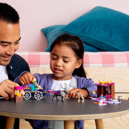 Child and adult enjoying LEGO Disney Frozen 2 Elsa's Wagon Adventure playset on a tabletop.