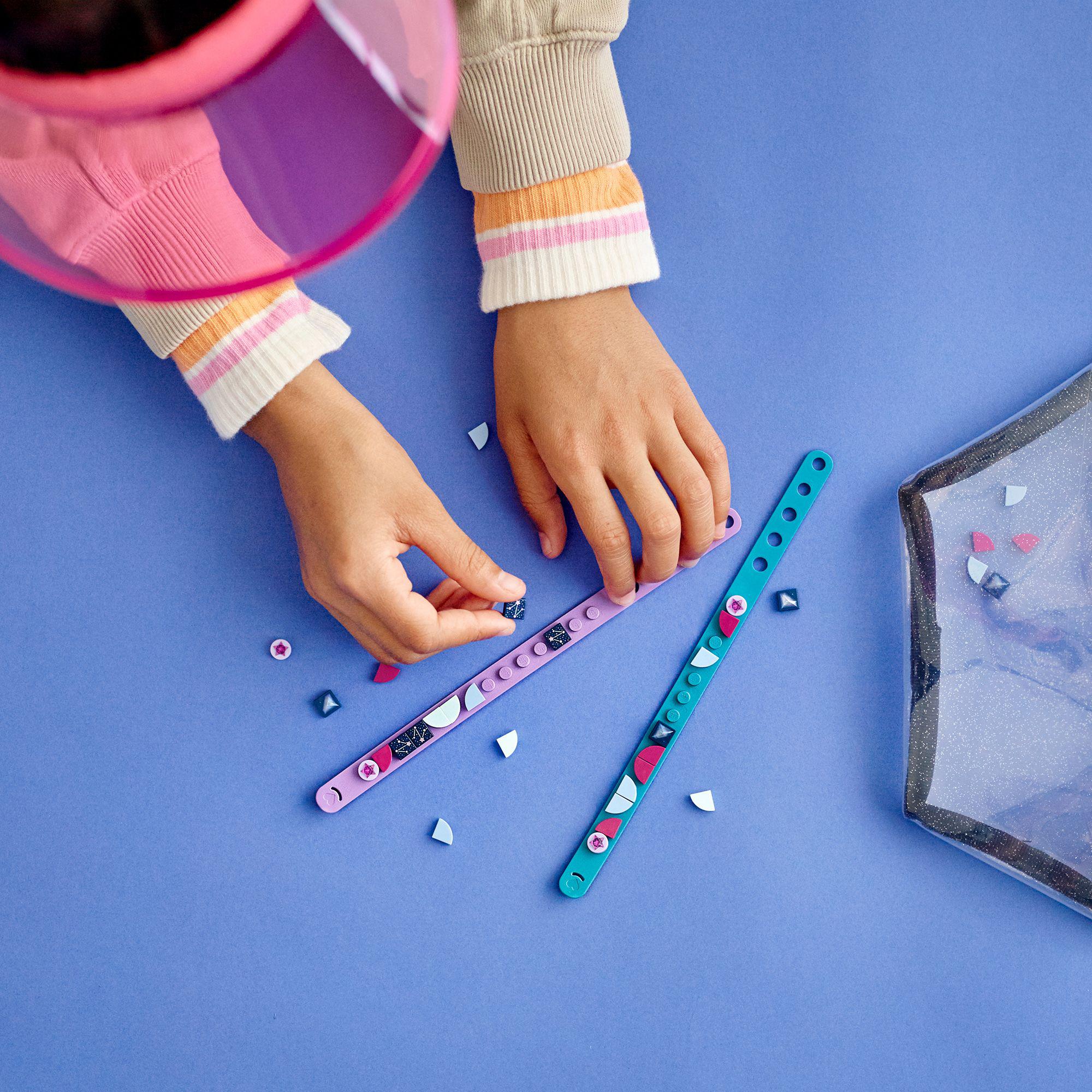Child creating with LEGO® DOTS Starlight Bracelets set featuring teal and purple bracelets and colorful tiles.