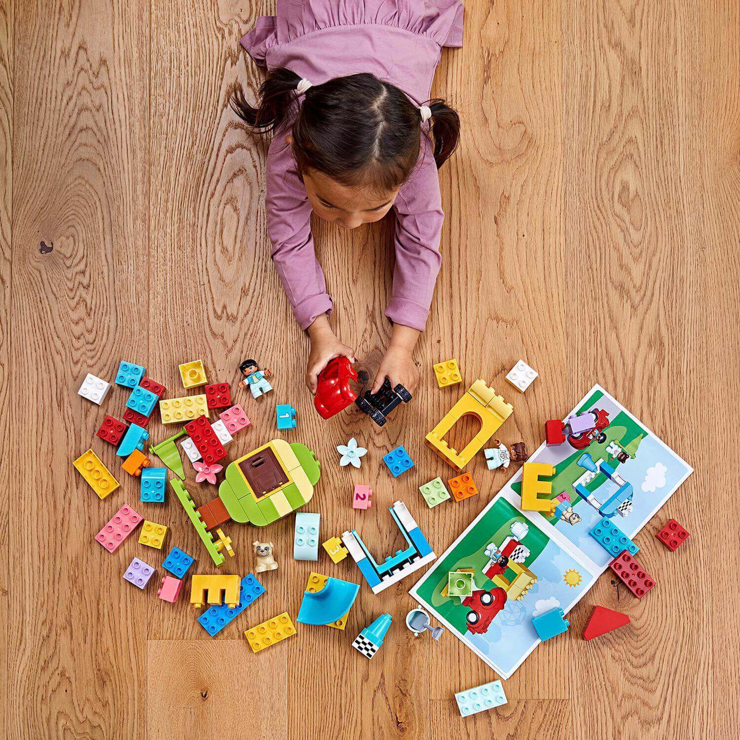 Toddler playing with LEGO® DUPLO Classic Deluxe Brick Box Set 10914, exploring colorful bricks and building fun.