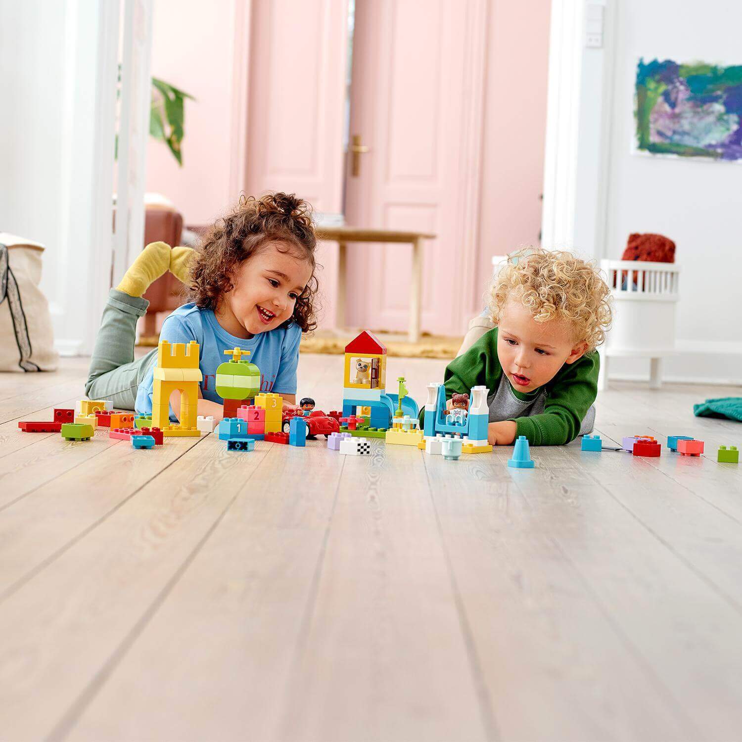 Children playing with LEGO® DUPLO Classic Deluxe Brick Box Set, featuring colorful bricks, a car, and fun accessories.
