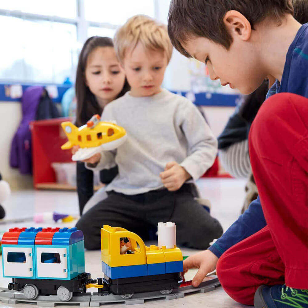 Children playing with LEGO® Education Coding Express train set, engaging in creative coding activities together.