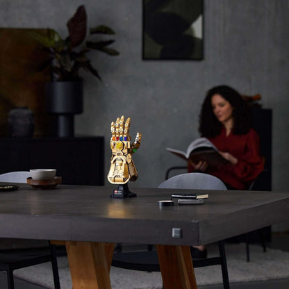 LEGO Marvel Infinity Gauntlet Thanos Set 76191 displayed on a table, with a woman reading in the background.