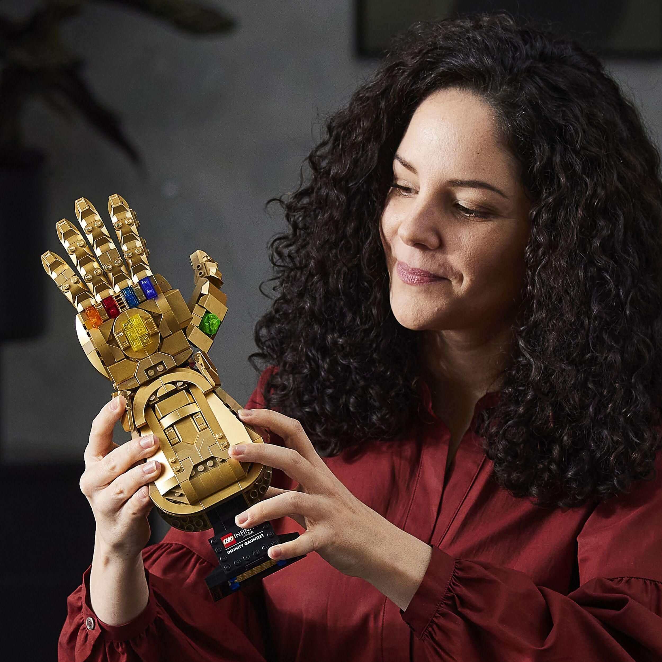 Adult woman admiring the LEGO® Marvel Infinity Gauntlet Thanos Set 76191 with 6 Infinity Stones and movable fingers.