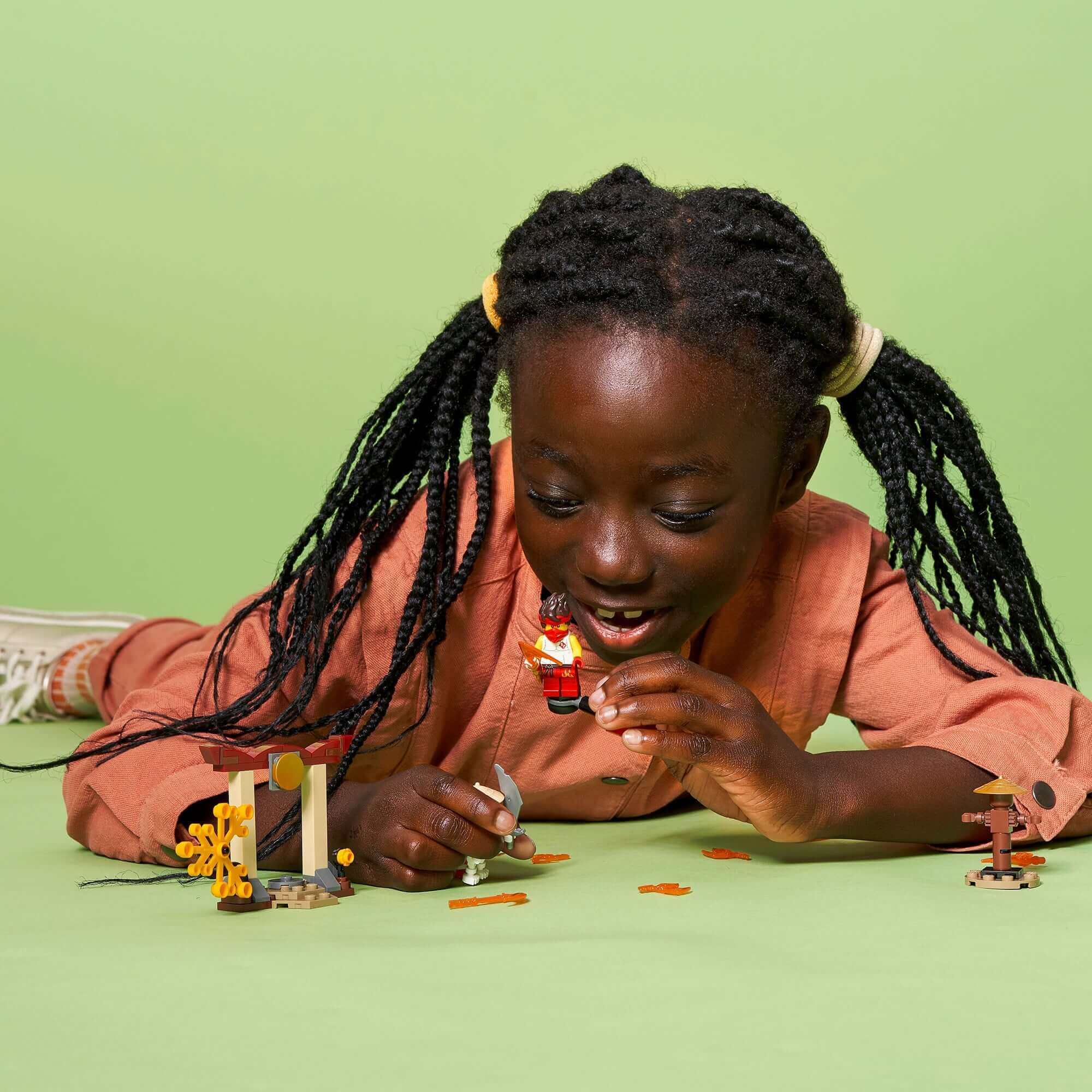 Child playing with LEGO® NINJAGO set, enjoying the action of Kai vs. Skulkin in an engaging scene.