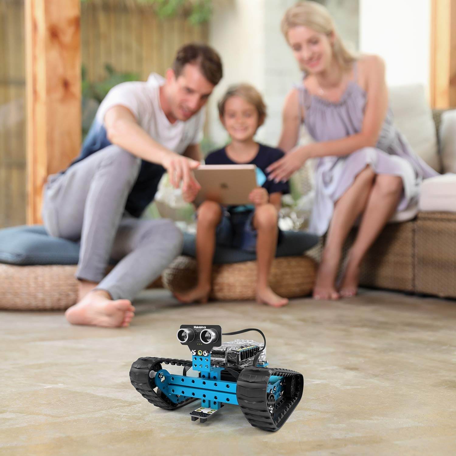 Family engaging with the Makeblock mBot Ranger robot kit on a living room floor, showcasing its interactive features.