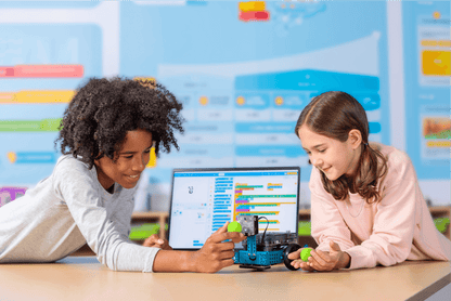 Two children engaging with the Makeblock mBot 2 robot while programming on a laptop.