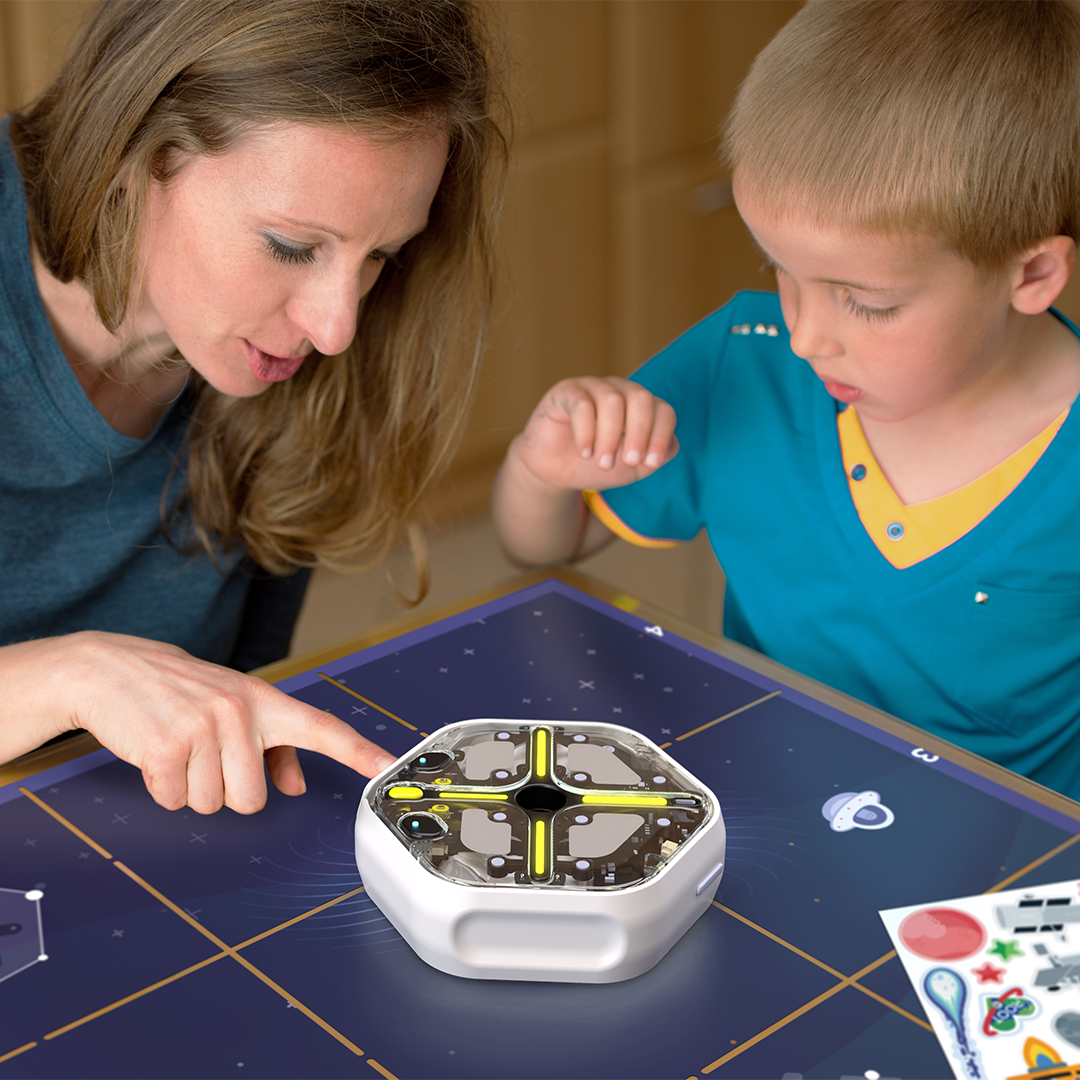 Parent and child engaging with the Root coding robot in a fun learning activity about coding in space.