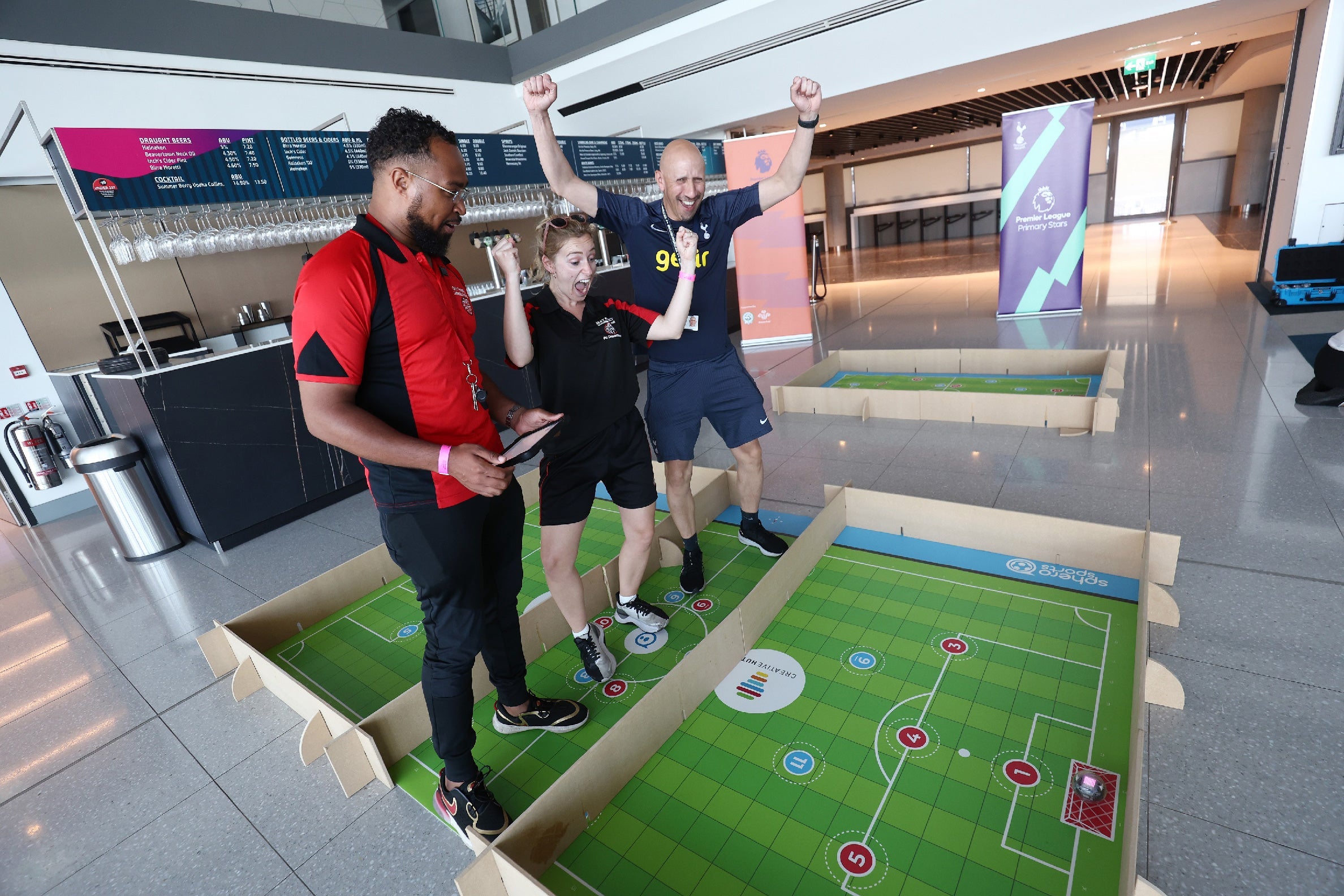 Three people celebrating a game in a sports-themed event, engaging on a tabletop soccer setup.