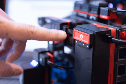 Close-up of a hand pressing the power button on a Sphero engineering kit for robotics education.