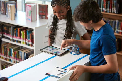 Students engaging with Sphero BOLT+ robot and tablet, promoting interactive learning in a library setting.