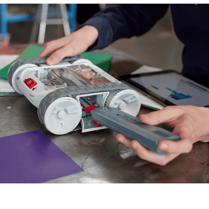 Hands inserting battery into Sphero RVR+ programmable robot, showcasing its customizable design and technology.