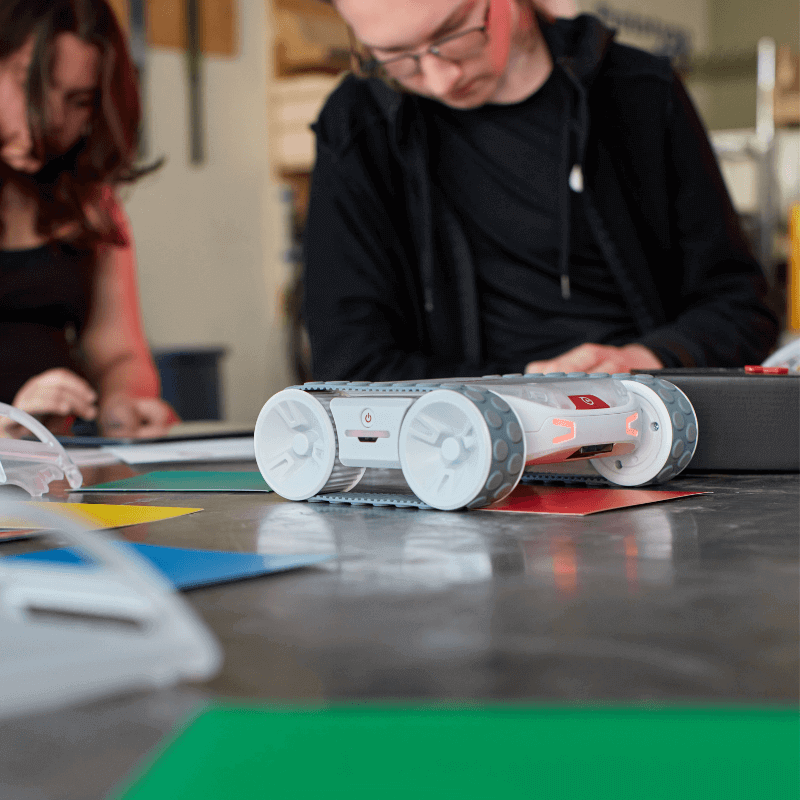 Sphero RVR+ robot on a table with students engaged in a programming activity, showcasing hands-on learning.