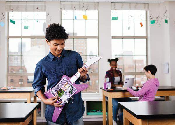 Student using littleBits Code Kit guitar invention in a classroom, showcasing hands-on coding and electronics learning.