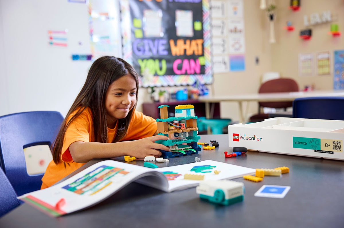 Girl building a colorful structure with educational blocks in a classroom, promoting hands-on learning.