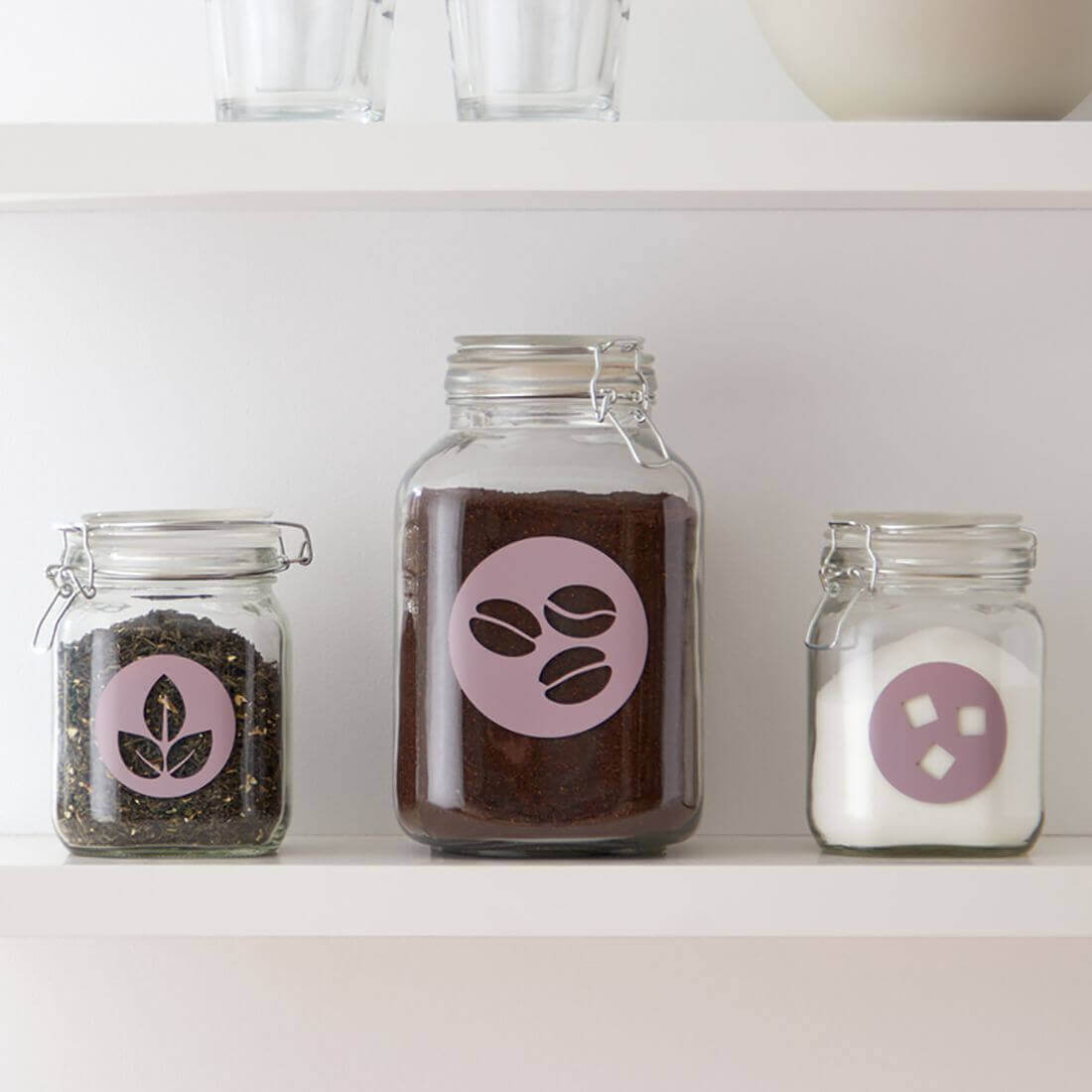 Three glass jars with Cricut Joy vinyl labels for coffee, tea, and sugar on a shelf.